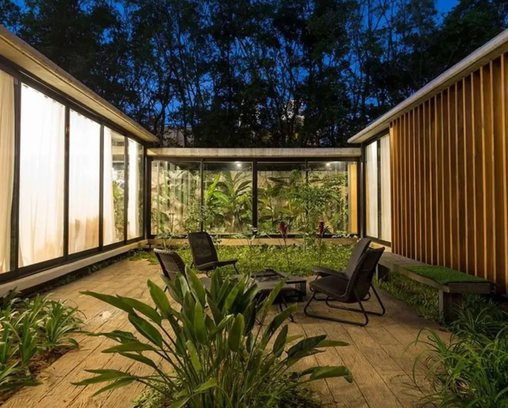 Night view of a biophilic courtyard in a luxury residence with vertical garden, wood finishes and integrated greenery.