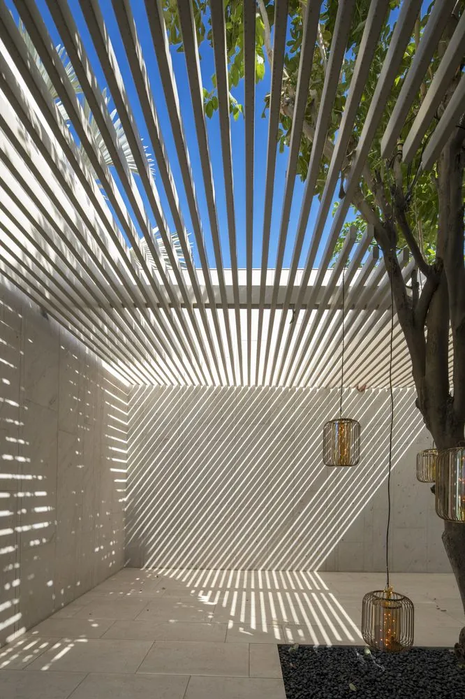Slatted pergola casting diagonal shade, dual seasonal design